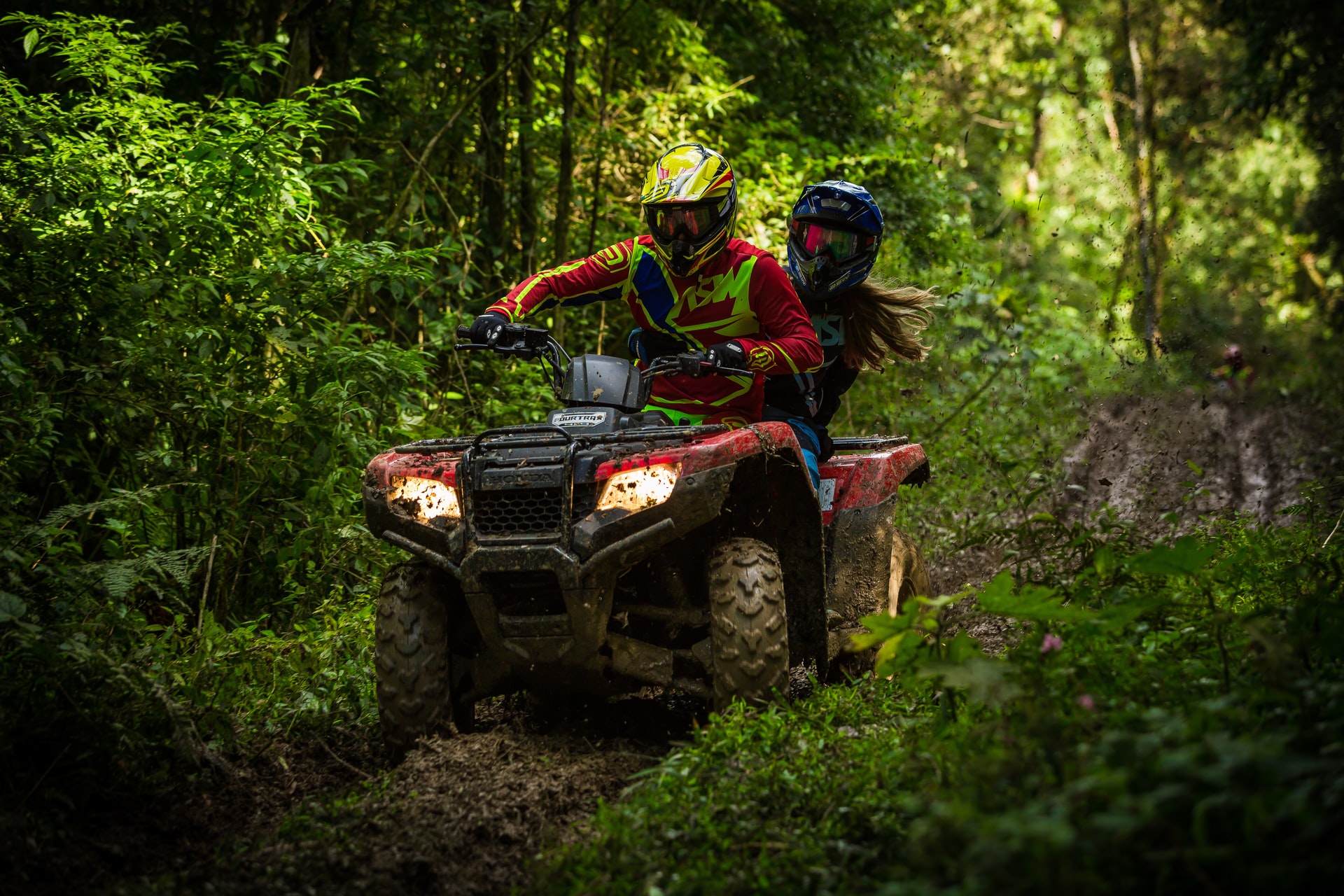 A pair riding an ATV in the woods representing ATV accidents in Ontario