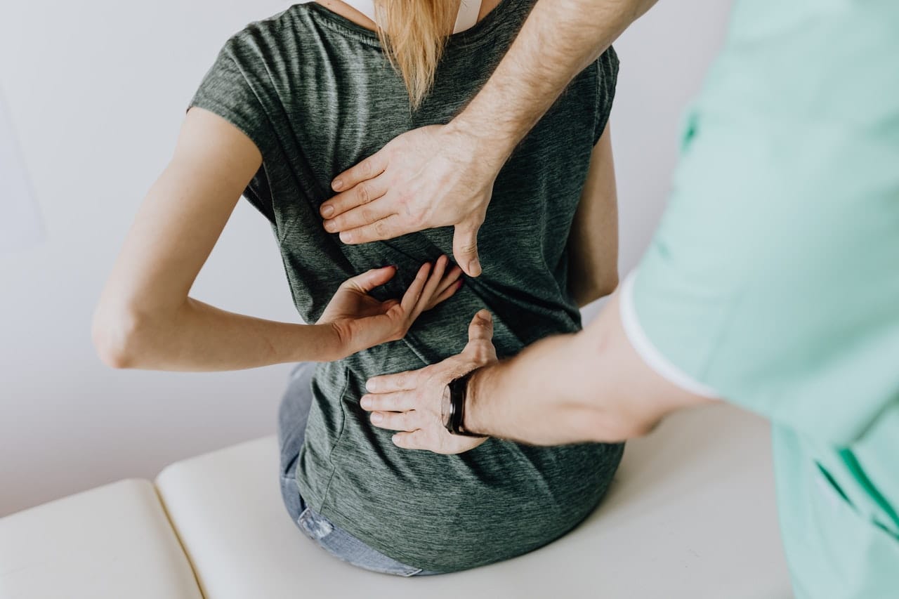 A doctor examining a woman's back representing chronic pain