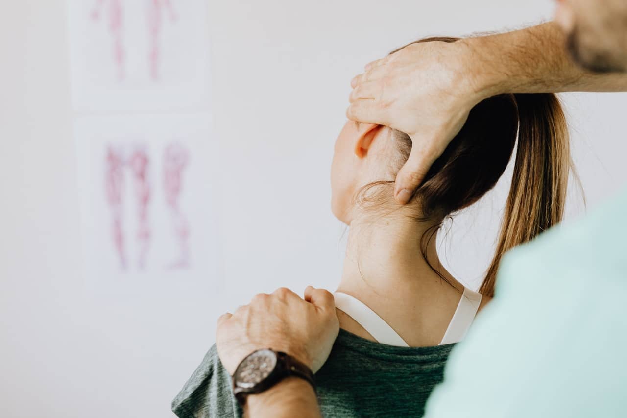 A doctor examining a client's neck representing soft tissue injuries
