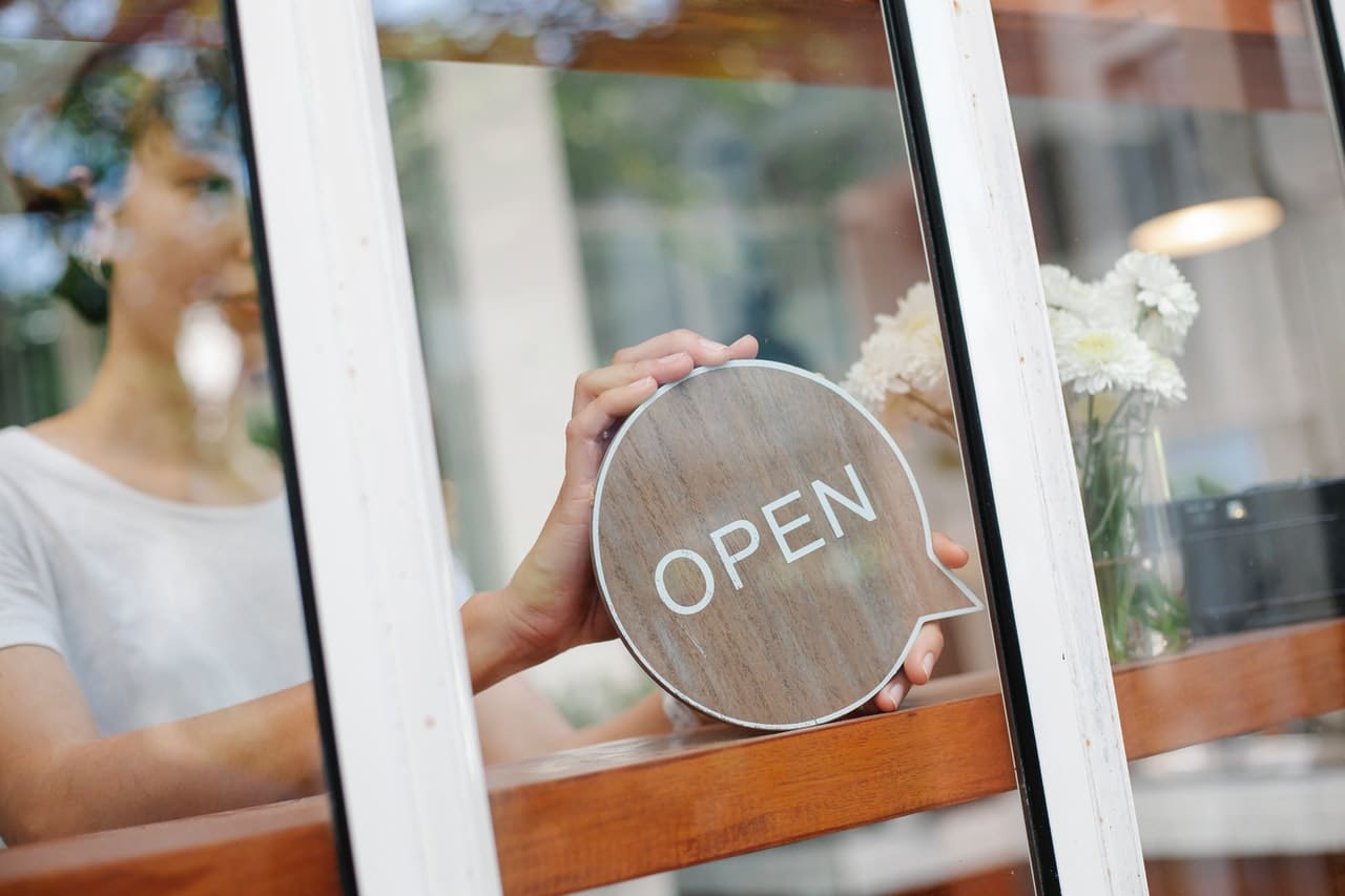 woman placing open sign in window