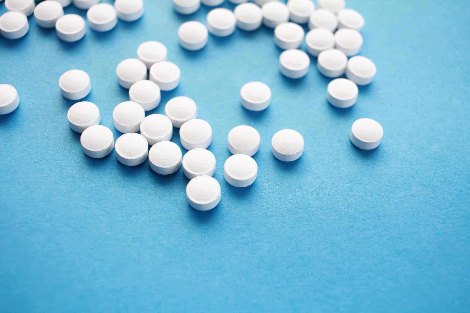 white opioid pills scattered on blue countertop