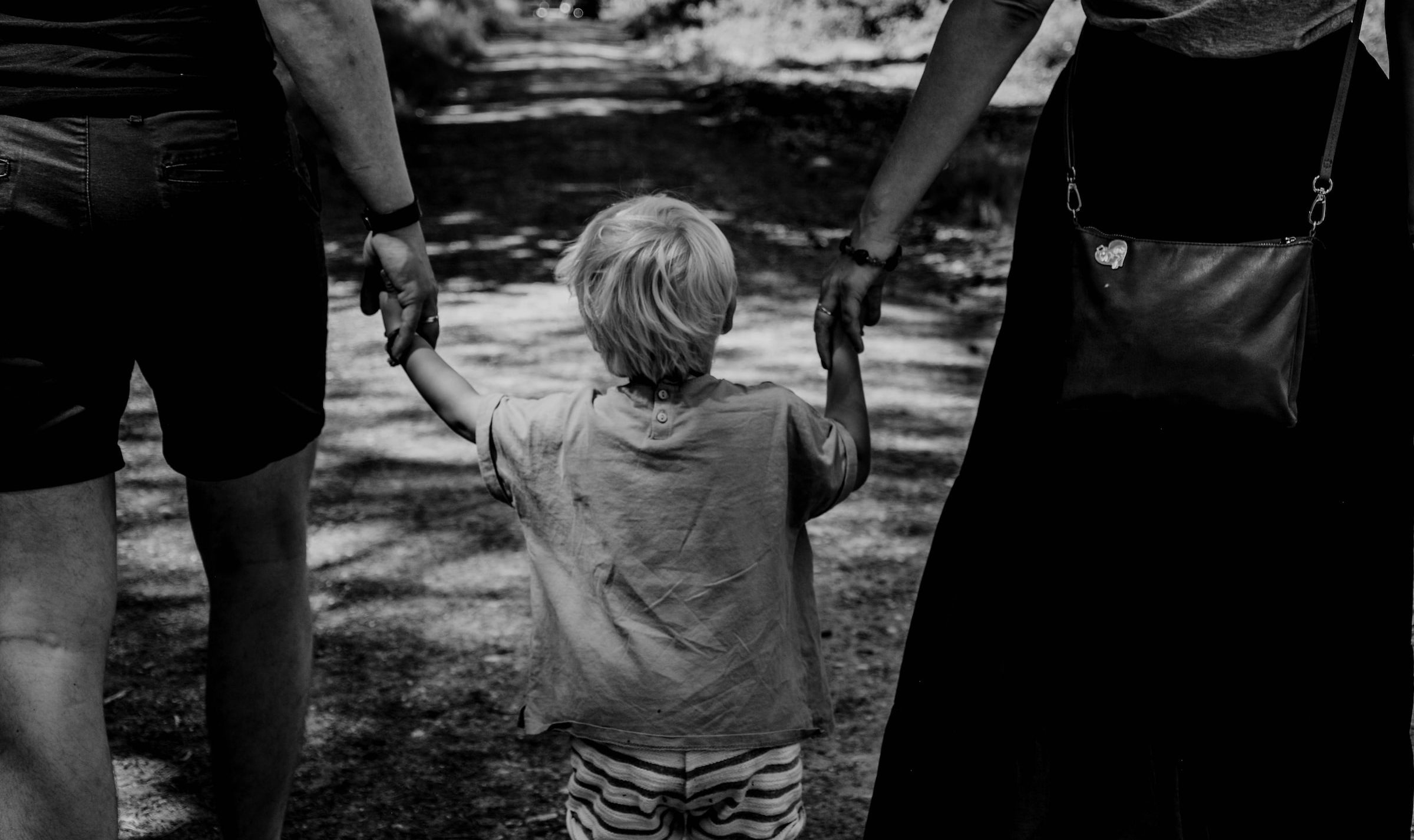 Black and white photo of a children between parents and holding both their hands, representing family and divorce law in Ottawa