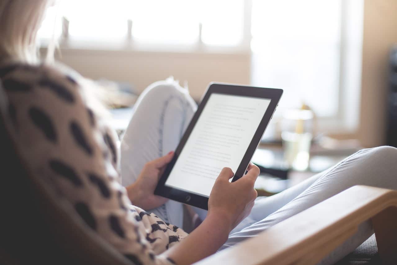 woman sitting in chair using tablet