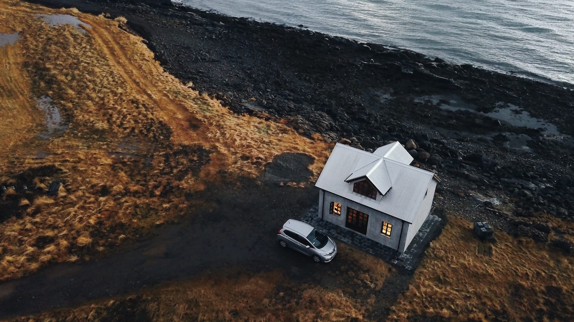 silver car parked in front of house on the ocean