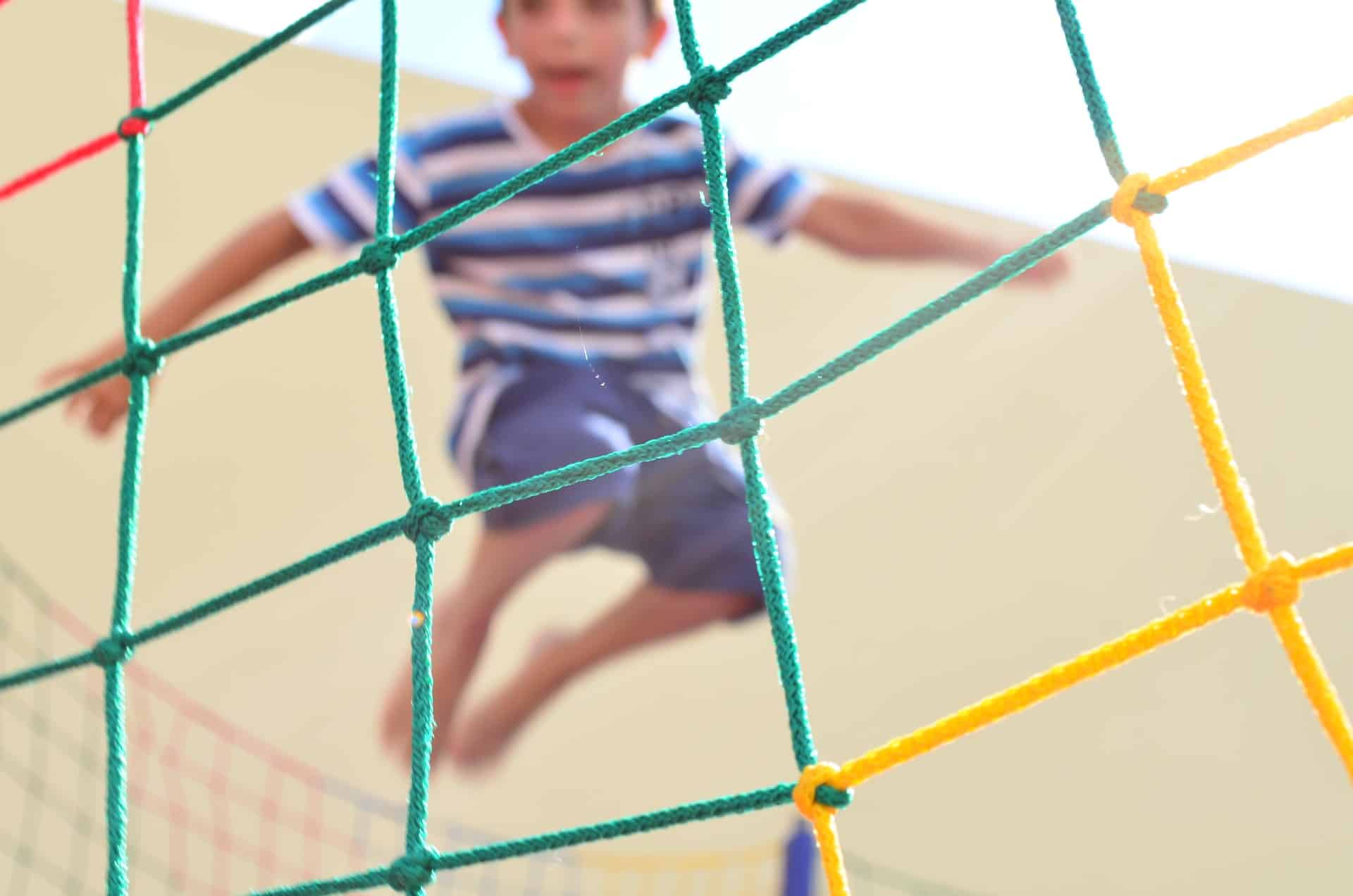 boy in blue and white shirt jumping on trampoline