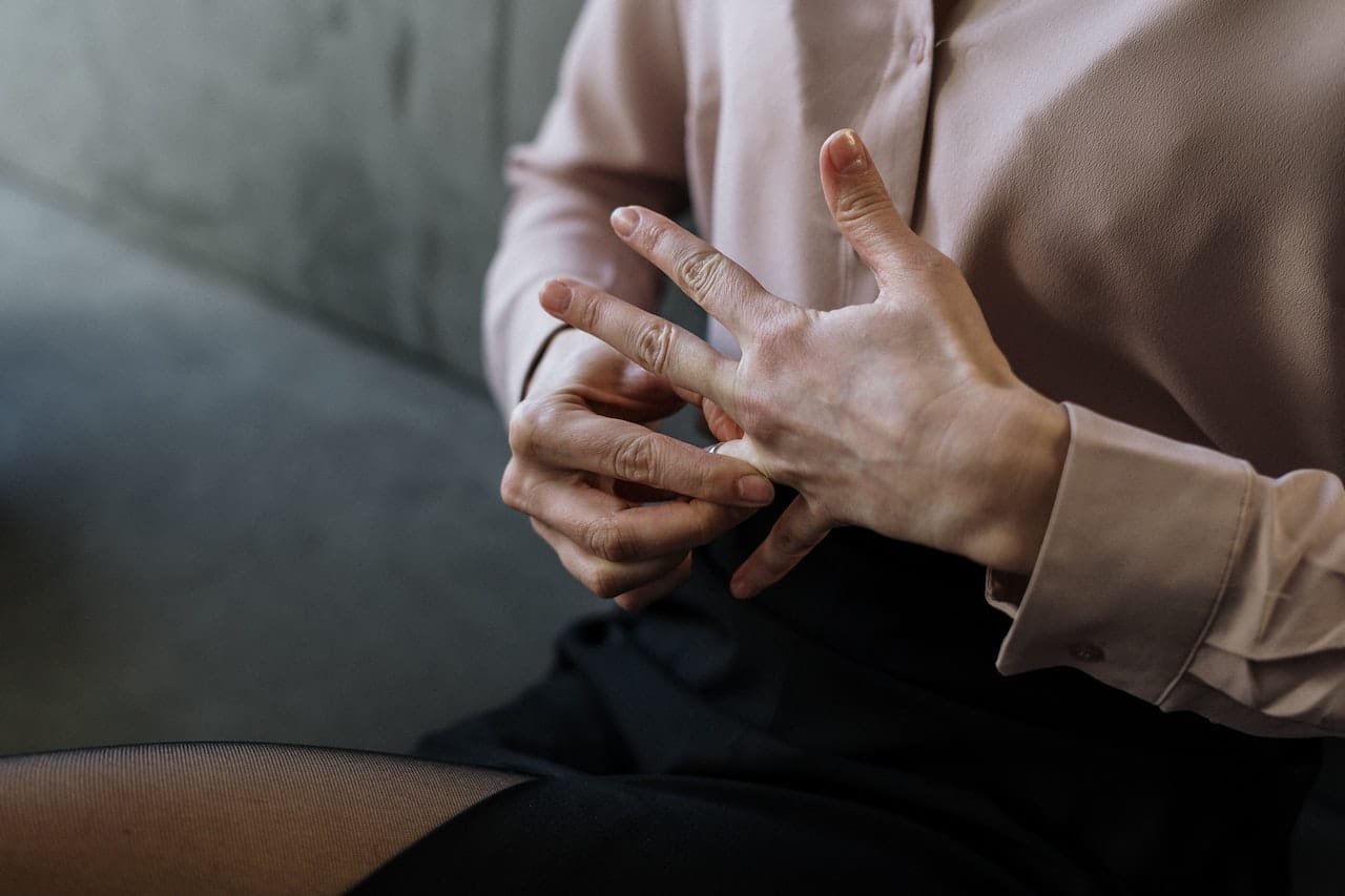 person in long sleeves removing wedding band