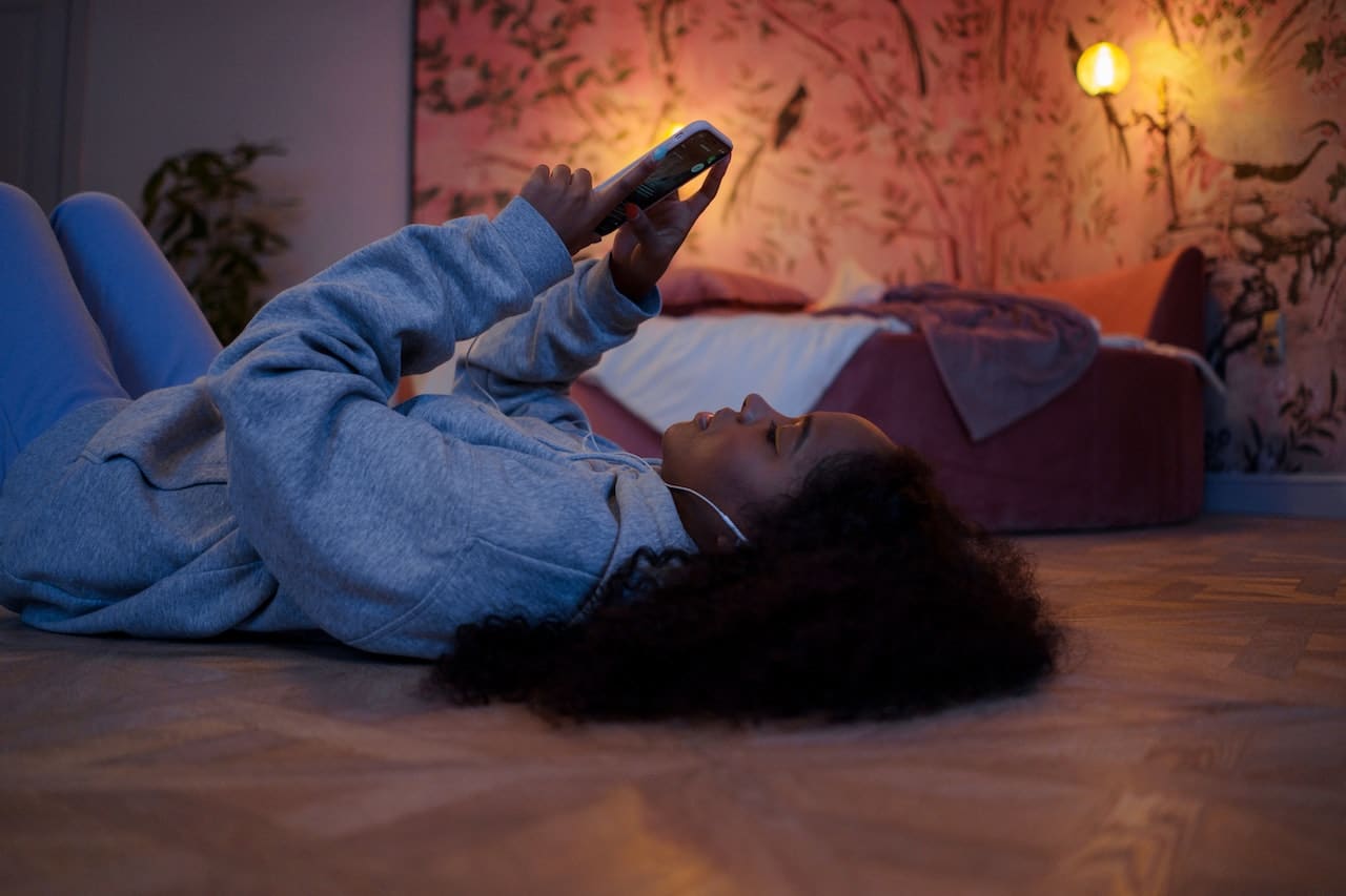 a woman looking at her phone while laying on the floor