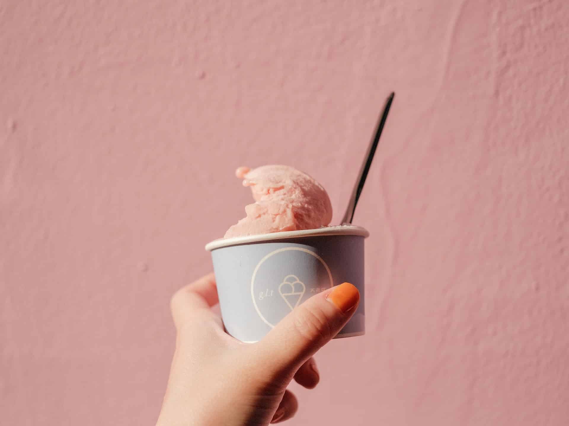 person holding ice cream cup and spoon