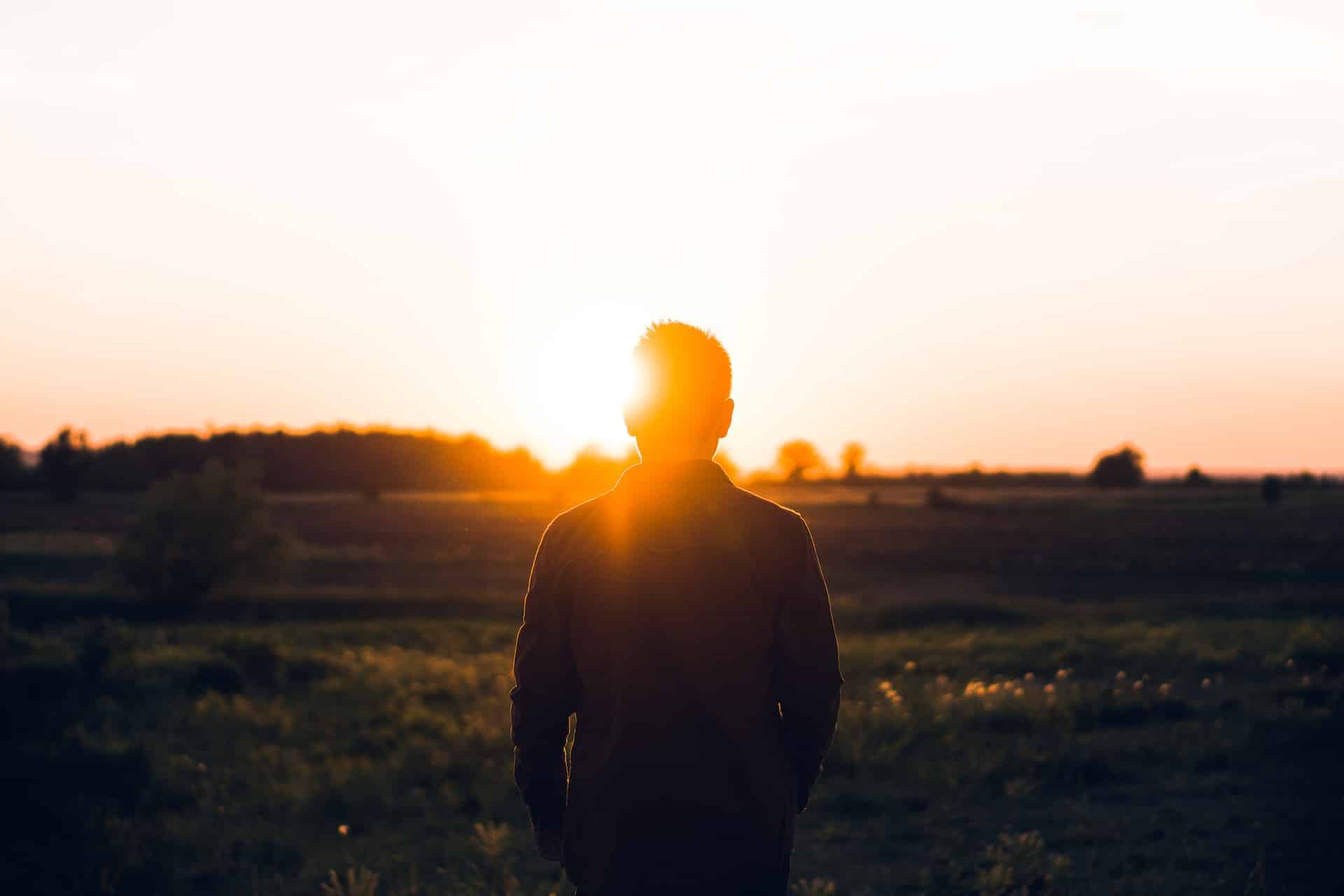 silhouette of man facing sunrise