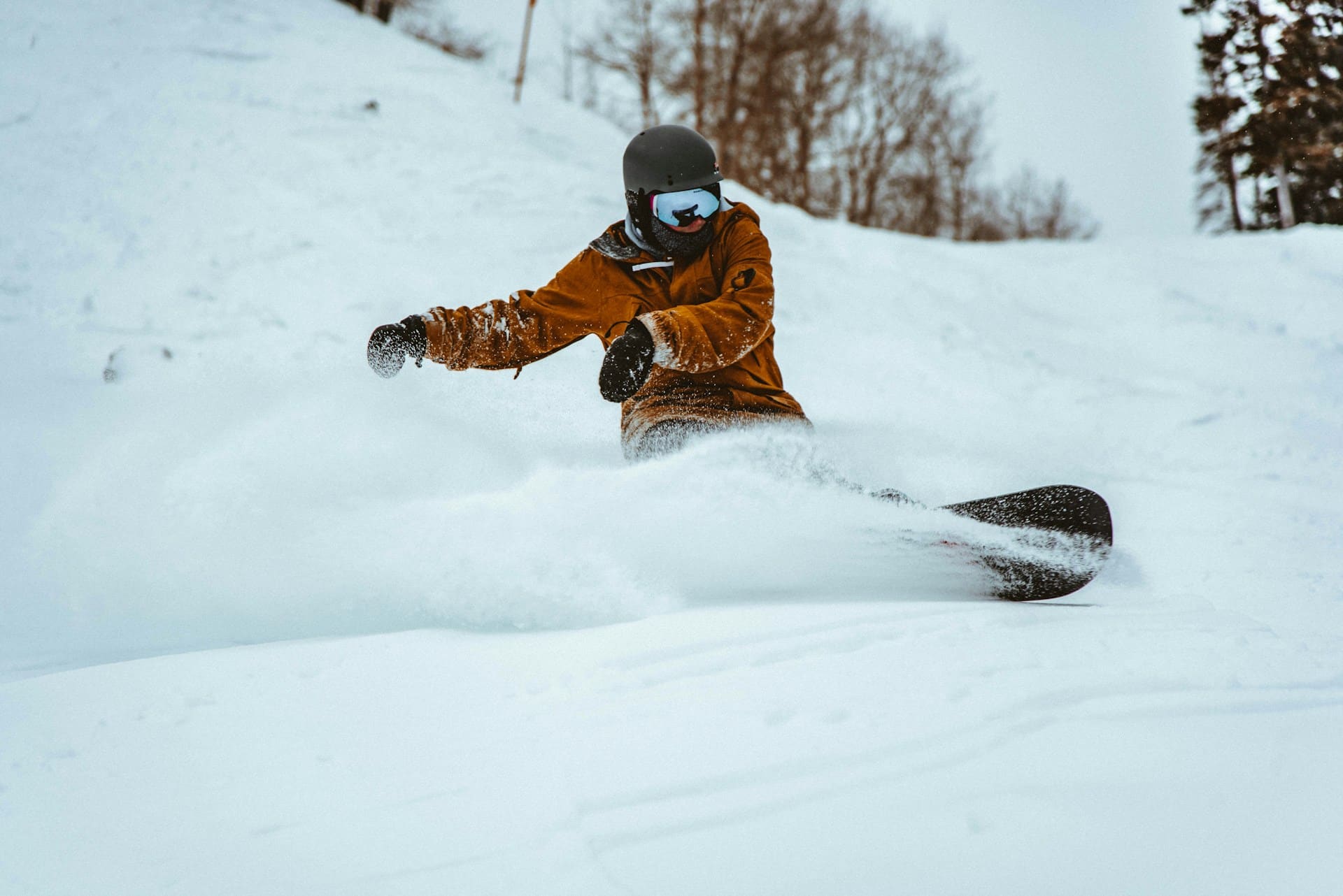 a person in a brown jacket snowboarding