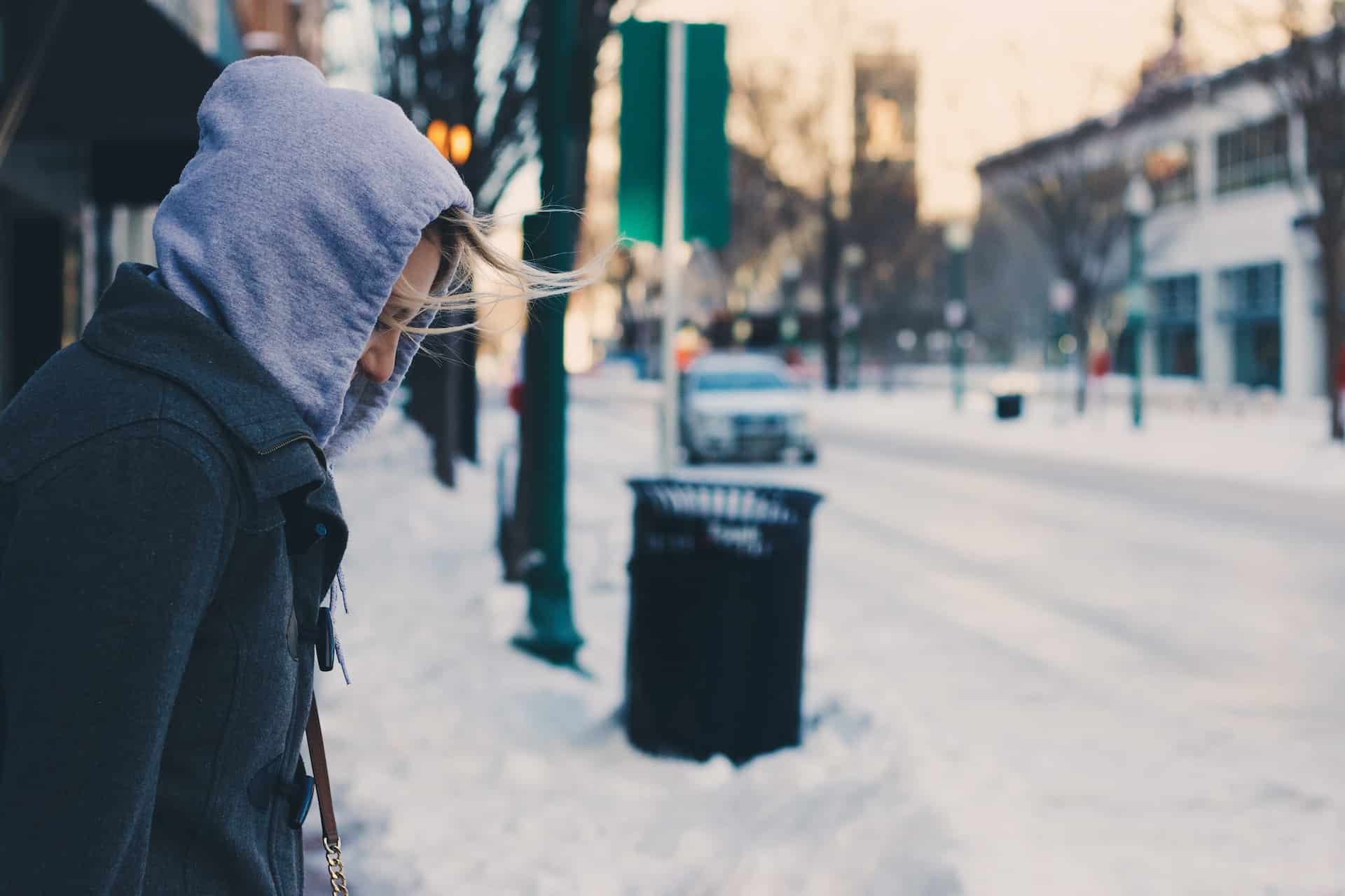 a person standing on sidewalk in the winter