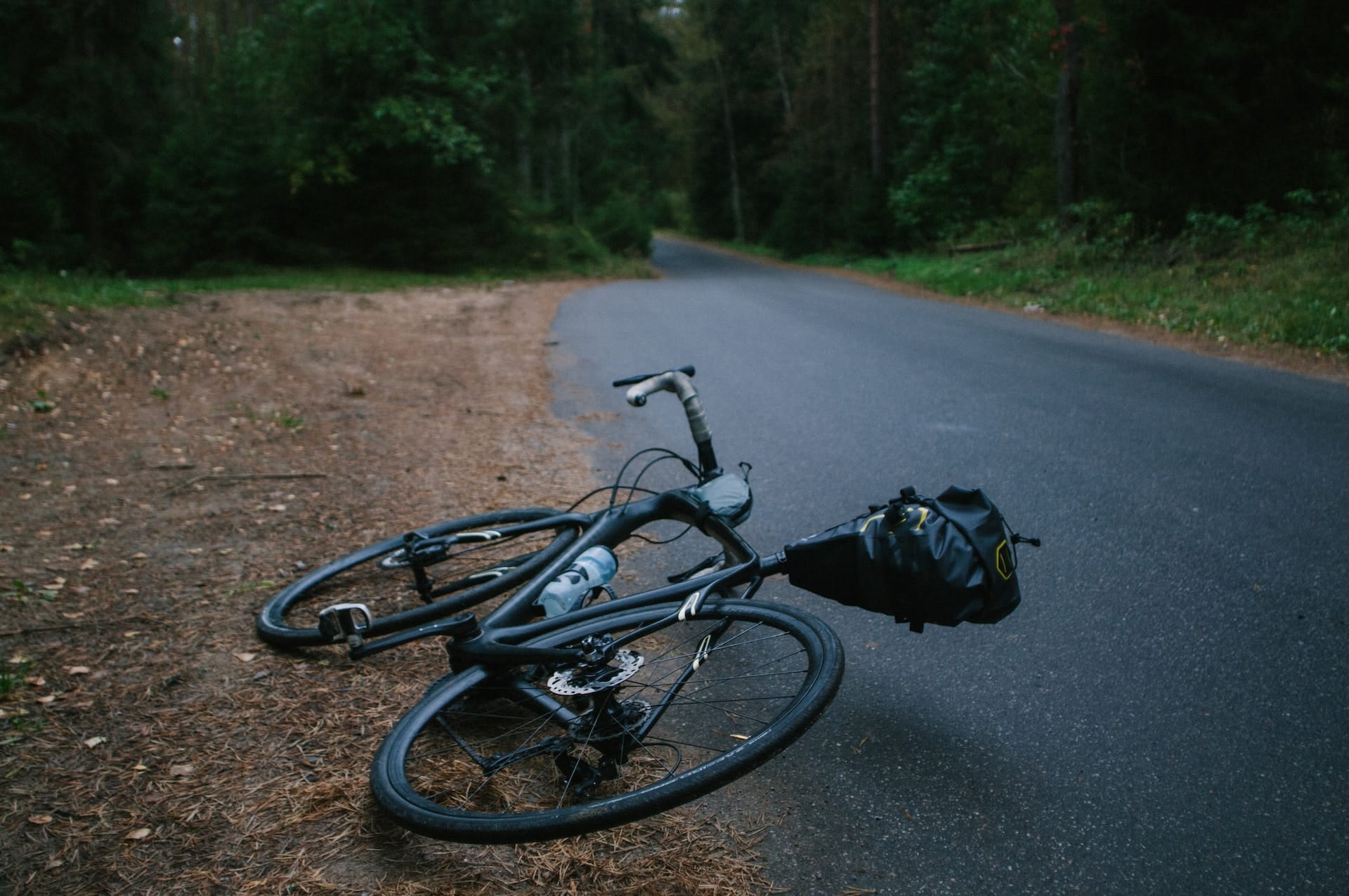 black road bike lying on side of road