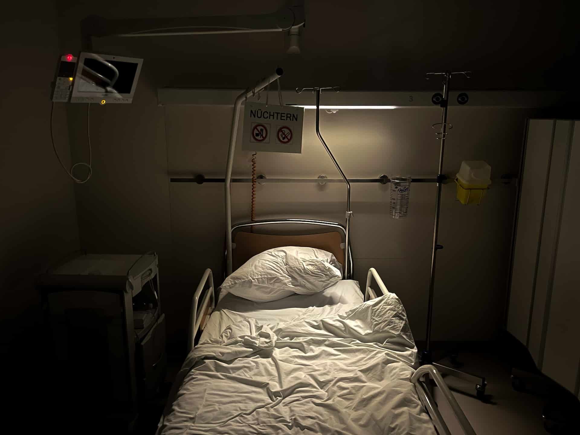 a hospital room with a light shining down on empty hospital bed