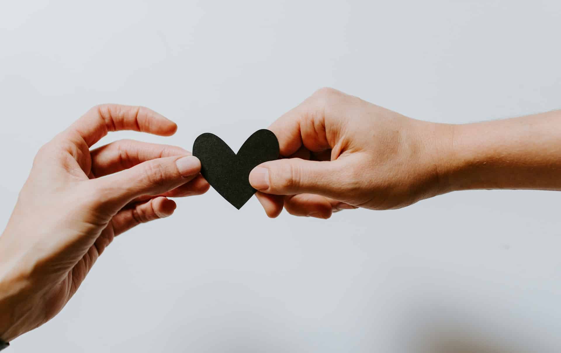 two people holding papercut out black heart