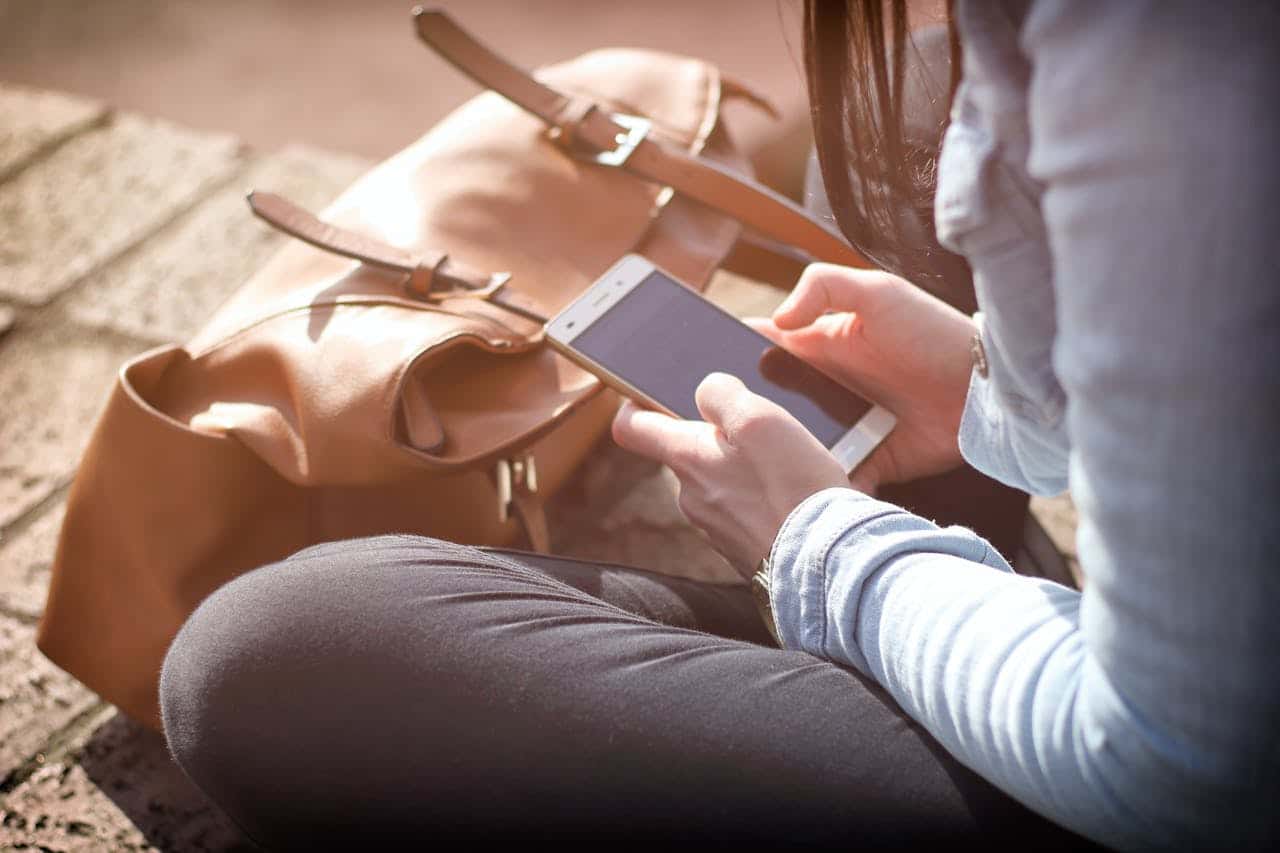 person using cell phone while sitting cross legged on the ground