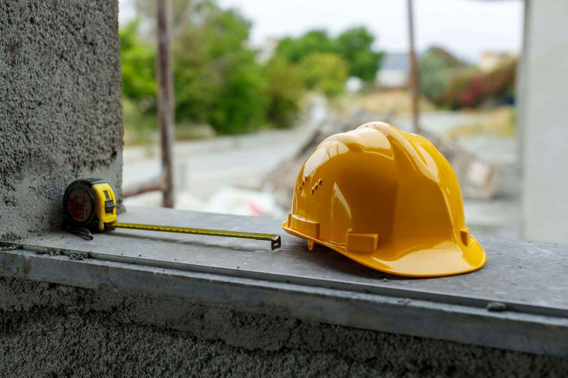 a hard hat and measuring tape sitting on edge of building