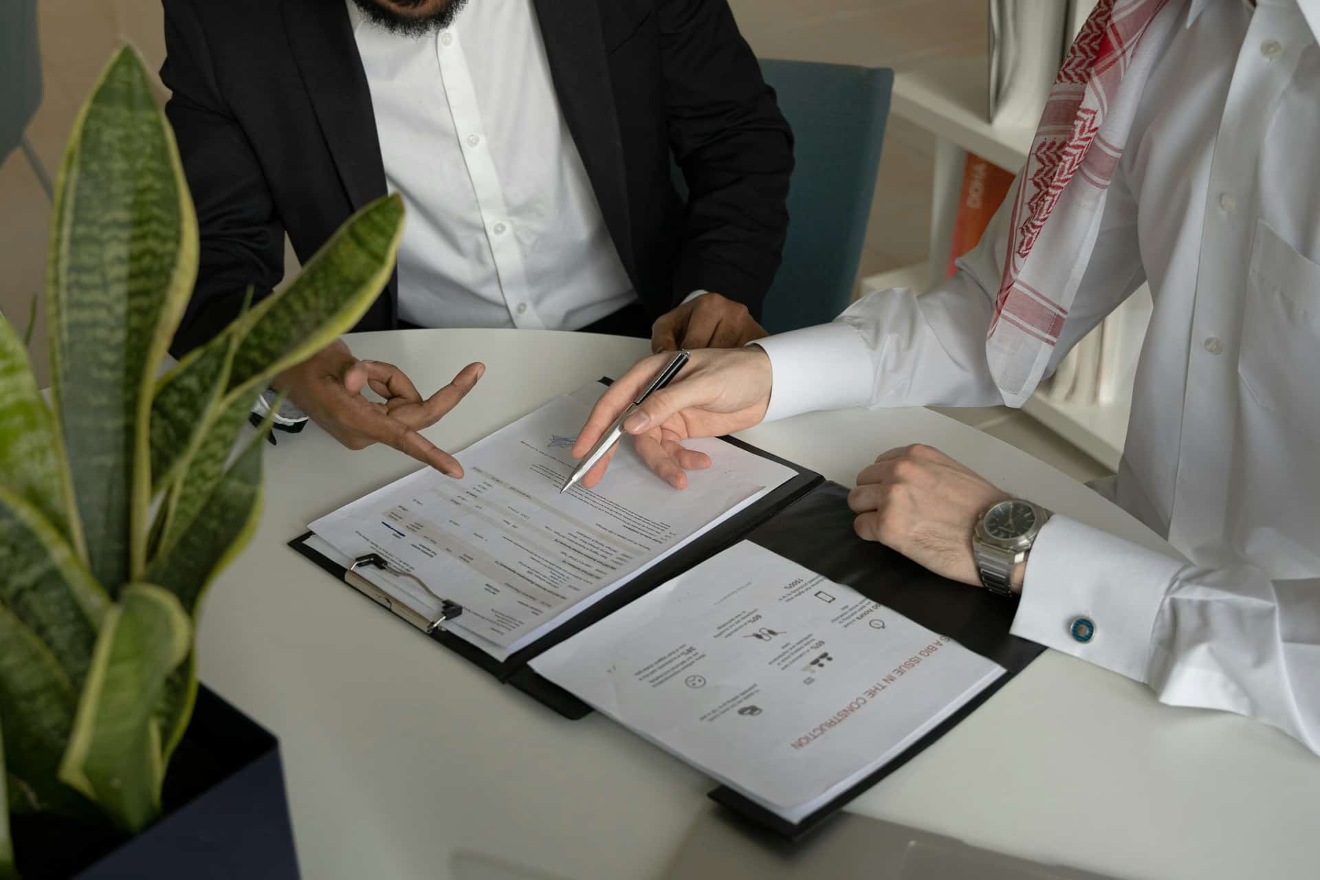Two men are seated at a table reviewing paperwork, representing service or supply contracts.