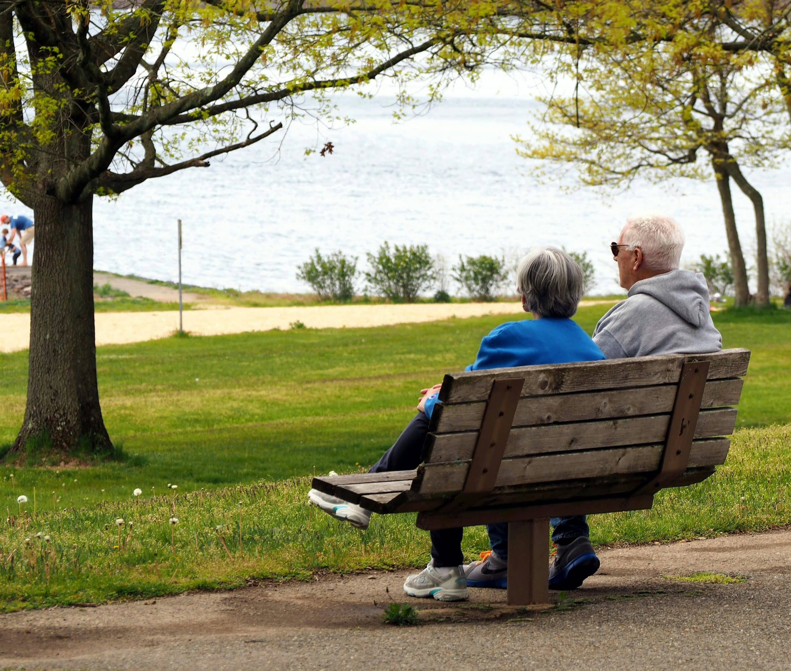 A senior couple sits on a park bench by a lake. This image can represent a couple considering their estate planning options, such as using an alter ego or joint partner trust in Ontario estate planning to manage their assets while they are alive.